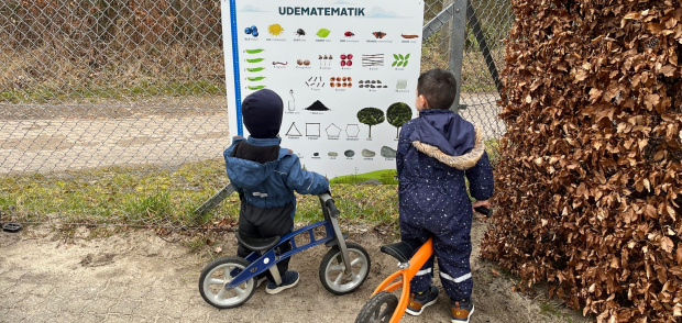 To drenge kigger på en tavle på legepladsen